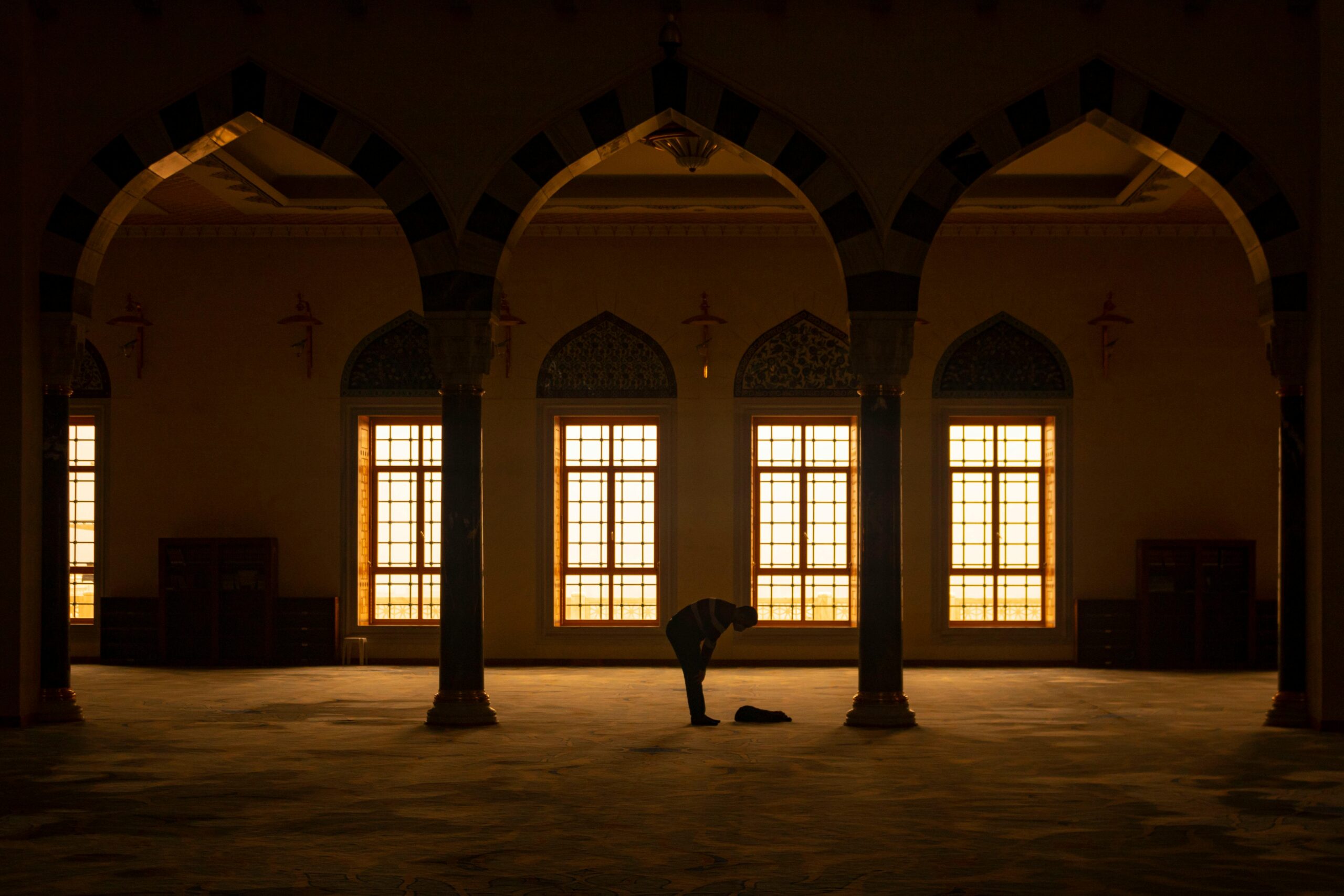 Serene scene of a man praying inside an arched mosque in Istanbul, Türkiye.